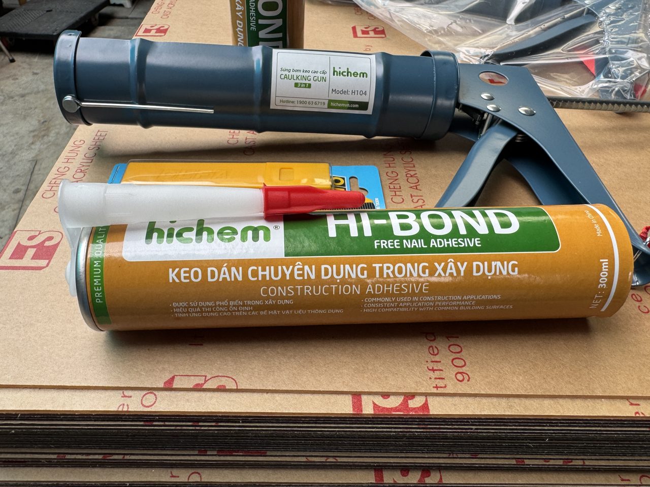 Súng bơm keo H104 đặt cạnh tuýp keo Hi-Bond 300 ml đã gắn vòi nhựa